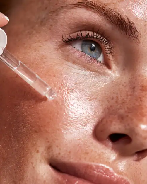 Applying a clear serum to the under eye area as part of a retinoid skincare routine