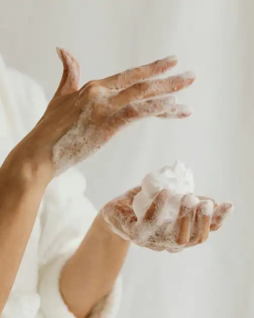 Woman in shower applying shower foam as part of self-care routine