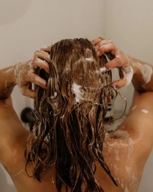 Woman in shower washing her hair as part of self-care routine