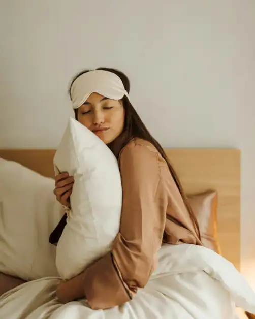 Woman hugging pillow in pyjama as part of self-care routine