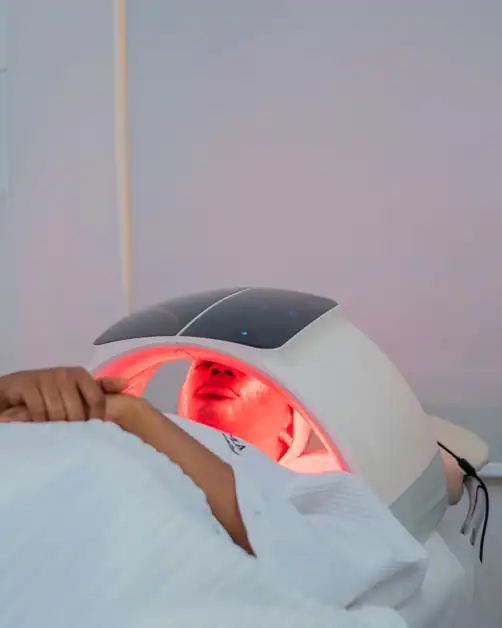 Woman using LED light therapy mask, one of the trending facial treatments in 2026