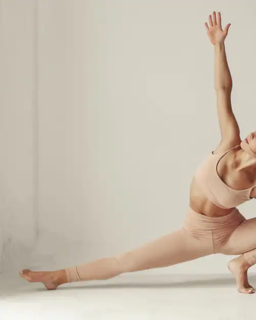 Woman in a side plank yoga pose wearing neutral activewear as part of a daily movement wellness habit